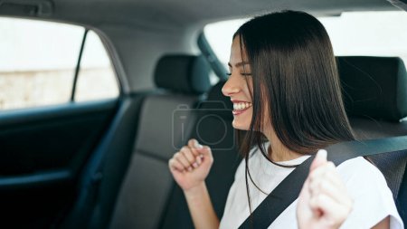 Téléchargez les photos : Jeune belle hispanique femme passager assis sur la voiture dansant dans la rue - en image libre de droit