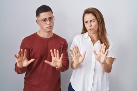 Photo for Mother and son standing together over isolated background moving away hands palms showing refusal and denial with afraid and disgusting expression. stop and forbidden. - Royalty Free Image