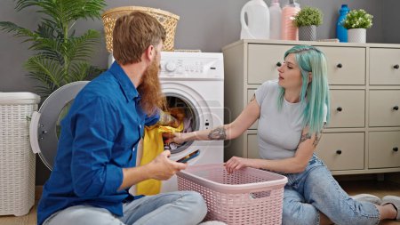 Téléchargez les photos : Homme et femme couple laver les vêtements en utilisant smartphone à la buanderie - en image libre de droit