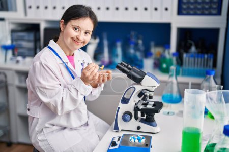 Photo for Young woman with down syndrome scientist smiling confident holding pill at laboratory - Royalty Free Image