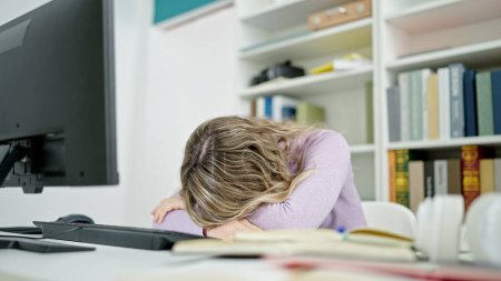 Photo for Young blonde woman student sleeping on table at classroom - Royalty Free Image