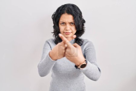 Foto de Mujer hispana con cabello oscuro de pie sobre fondo aislado expresión de rechazo cruzando los dedos haciendo signo negativo - Imagen libre de derechos