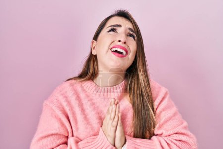 Photo for Young hispanic woman standing over pink background begging and praying with hands together with hope expression on face very emotional and worried. begging. - Royalty Free Image