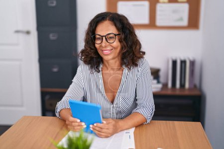 Téléchargez les photos : Middle age woman business worker smiling confident using touchpad at office - en image libre de droit