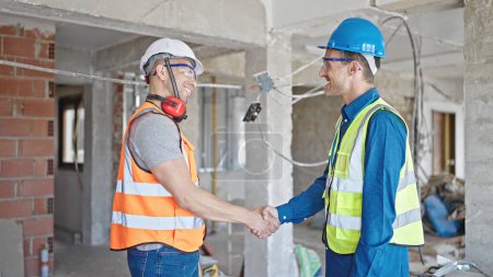 Téléchargez les photos : Deux hommes constructeurs serrent la main parlant sur le chantier de construction - en image libre de droit