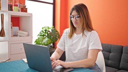 Téléchargez les photos : Jeune femme blonde utilisant un ordinateur portable souriant à la salle à manger - en image libre de droit