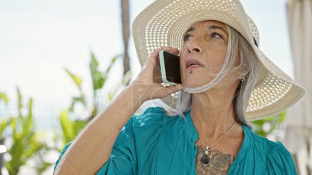 Foto de Turista mujer de pelo gris de mediana edad hablando en smartphone en la calle - Imagen libre de derechos