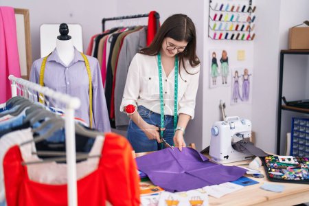 Téléchargez les photos : Jeune femme caucasienne tailleur souriant tissu de coupe confiant au magasin de tailleur - en image libre de droit