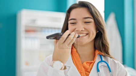 Photo for Young beautiful hispanic woman doctor sending voice message smiling at clinic - Royalty Free Image
