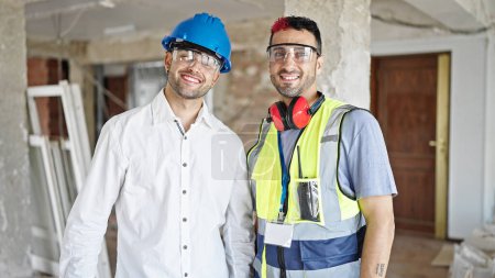 Téléchargez les photos : Deux hommes constructeur et architecte souriant confiant debout ensemble sur le chantier de construction - en image libre de droit