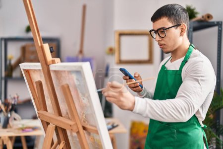 Téléchargez les photos : Jeune homme artiste utilisant un smartphone dessin au studio d'art - en image libre de droit
