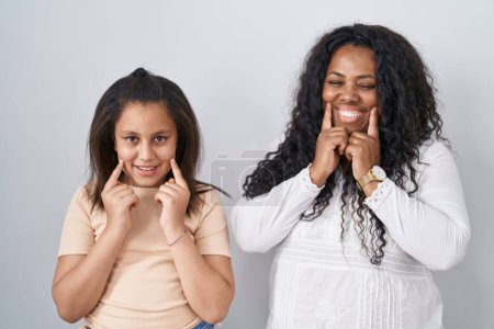 Téléchargez les photos : Mère et jeune fille debout sur fond blanc souriant avec la bouche ouverte, les doigts pointant et forçant sourire joyeux - en image libre de droit