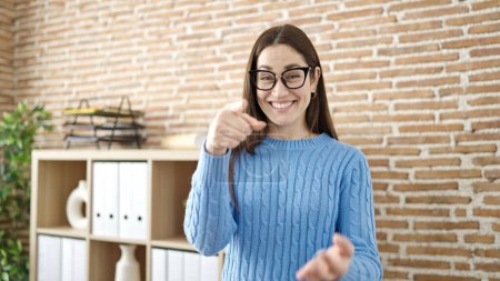 Téléchargez les photos : Jeune femme caucasienne travailleur d'affaires souriant confiant pointant du doigt à la caméra au bureau - en image libre de droit