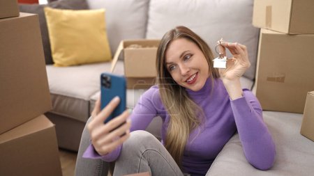 Foto de Joven mujer rubia hacer selfie por teléfono inteligente con llave en el nuevo hogar - Imagen libre de derechos