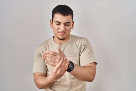Téléchargez les photos : Jeune homme arabe portant un t-shirt décontracté souffrant de douleur aux mains et aux doigts, inflammation de l'arthrite - en image libre de droit