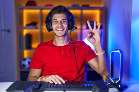 Photo for Young hispanic man playing video games showing and pointing up with fingers number three while smiling confident and happy. - Royalty Free Image