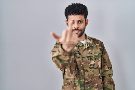 Foto de Arab man wearing camouflage army uniform showing middle finger, impolite and rude fuck off expression - Imagen libre de derechos