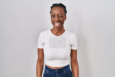 Photo for Beautiful black woman standing over isolated background winking looking at the camera with sexy expression, cheerful and happy face. - Royalty Free Image