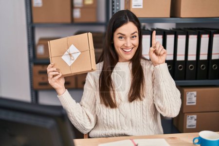 Photo for Young brunette woman working at small business ecommerce surprised with an idea or question pointing finger with happy face, number one - Royalty Free Image