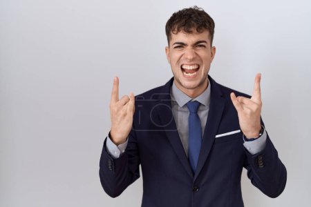 Photo for Young hispanic business man wearing suit and tie shouting with crazy expression doing rock symbol with hands up. music star. heavy concept. - Royalty Free Image