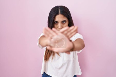 Téléchargez les photos : Jeune femme arabe debout sur fond rose expression de rejet croisement des bras et des paumes faisant signe négatif, visage en colère - en image libre de droit