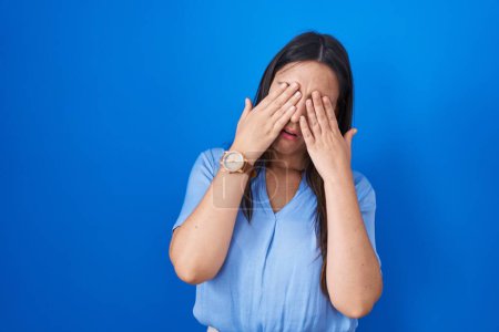 Photo for Young brunette woman standing over blue background rubbing eyes for fatigue and headache, sleepy and tired expression. vision problem - Royalty Free Image