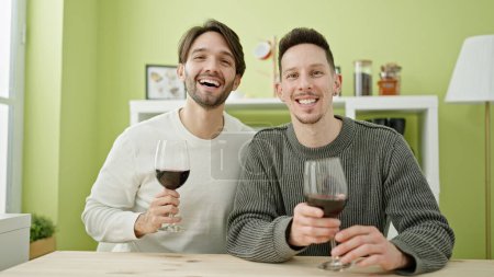 Téléchargez les photos : Deux hommes couple souriant verre de vin confiant à boire à la salle à manger - en image libre de droit
