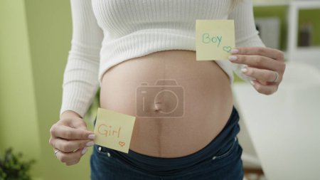 Photo for Young pregnant woman holding girl and boy reminder papers at dinning room - Royalty Free Image