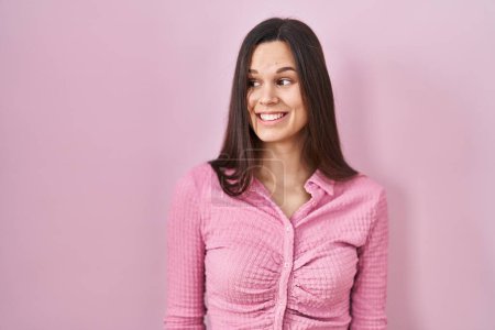 Téléchargez les photos : Young hispanic woman standing over pink background smiling looking to the side and staring away thinking. - en image libre de droit
