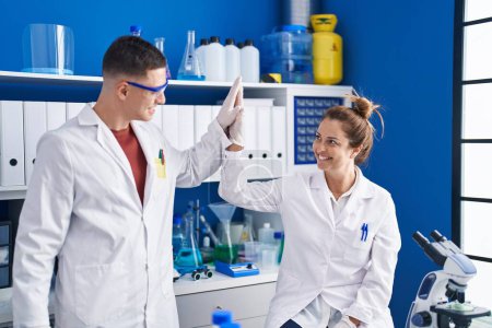 Téléchargez les photos : Homme et femme scientifiques haute cinq avec les mains levées au laboratoire - en image libre de droit