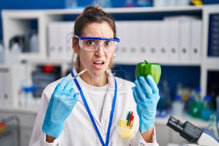 Photo for Young hispanic woman working at scientist laboratory with vegetables clueless and confused expression. doubt concept. - Royalty Free Image