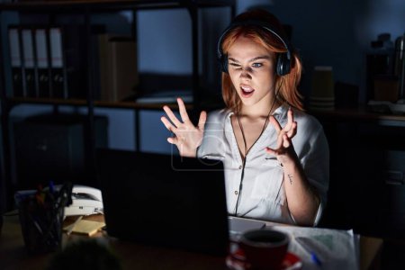 Photo for Young caucasian woman working at the office at night crazy and mad shouting and yelling with aggressive expression and arms raised. frustration concept. - Royalty Free Image