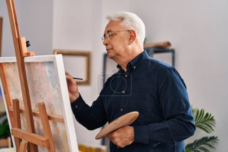 Foto de Hombre mayor dibujando con expresión seria en el estudio de arte - Imagen libre de derechos