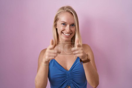 Photo for Young caucasian woman standing over pink background pointing fingers to camera with happy and funny face. good energy and vibes. - Royalty Free Image