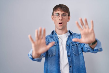 Photo for Caucasian blond man standing wearing glasses doing stop gesture with hands palms, angry and frustration expression - Royalty Free Image