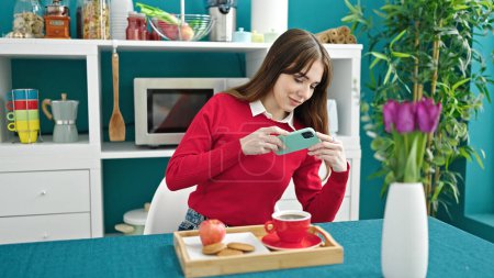 Photo for Young hispanic woman make photo to breakfast by smartphone at dinning room - Royalty Free Image
