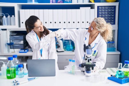 Téléchargez les photos : Deux femmes scientifiques se cognent les poings au laboratoire - en image libre de droit