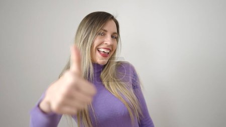 Téléchargez les photos : Jeune femme blonde souriante confiante faire ok signe avec le pouce vers le haut sur fond blanc isolé - en image libre de droit