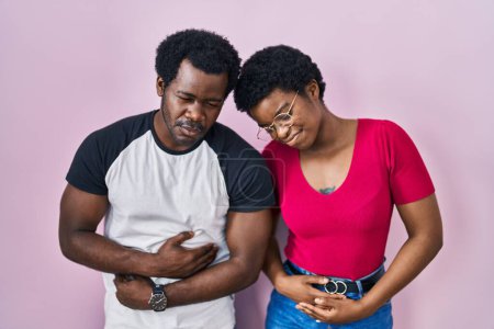 Photo for Young african american couple standing over pink background with hand on stomach because indigestion, painful illness feeling unwell. ache concept. - Royalty Free Image
