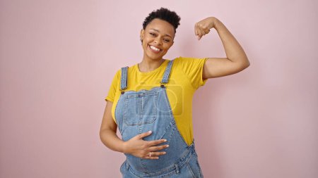 Photo for Young pregnant woman smiling confident doing strong gesture over isolated pink background - Royalty Free Image