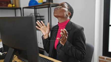 Foto de Trabajadora de negocios afroamericana jugando con pluma en la boca en la oficina - Imagen libre de derechos