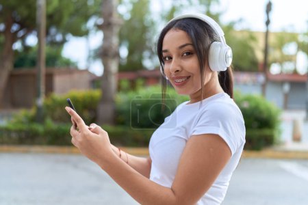 Téléchargez les photos : Jeune femme arabe écoutant de la musique dans la rue - en image libre de droit