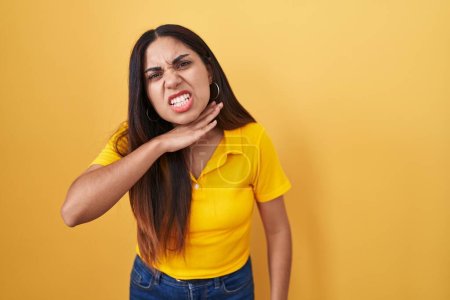 Foto de Mujer árabe joven de pie sobre fondo amarillo cortando la garganta con la mano como cuchillo, amenazan la agresión con violencia furiosa - Imagen libre de derechos