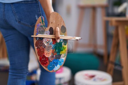 Photo for Young woman artist holding paintbrushes and palette at art studio - Royalty Free Image