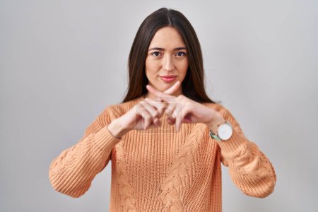 Téléchargez les photos : Jeune femme brune debout sur fond blanc expression de rejet croisement des doigts faisant signe négatif - en image libre de droit
