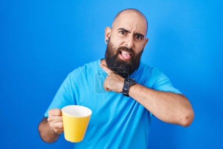 Photo for Young hispanic man with beard and tattoos drinking a cup of coffee cutting throat with hand as knife, threaten aggression with furious violence - Royalty Free Image