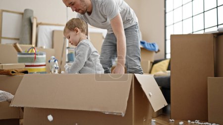 Foto de Padre e hijo jugando con caja de cartón en casa nueva - Imagen libre de derechos