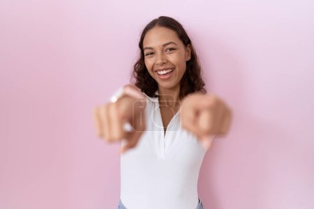 Foto de Young hispanic woman wearing casual white t shirt pointing to you and the camera with fingers, smiling positive and cheerful - Imagen libre de derechos