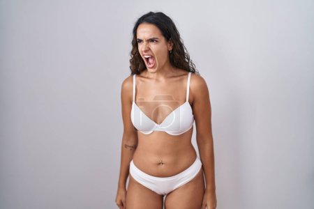 Photo for Young hispanic woman wearing white lingerie angry and mad screaming frustrated and furious, shouting with anger. rage and aggressive concept. - Royalty Free Image