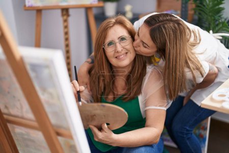 Foto de Madre e hija artistas abrazándose unos a otros dibujando y besándose en el estudio de arte - Imagen libre de derechos